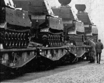Image of C Battery howitzers being loaded on flatbed railroad cars.